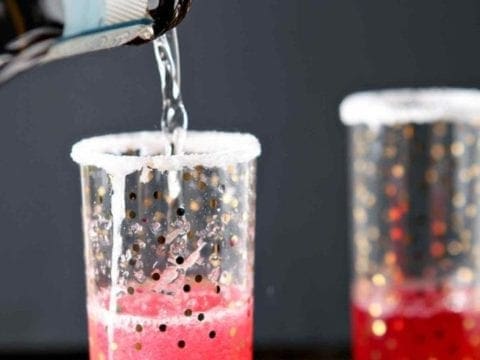 pouring champagne in a glass with pomegranate juice