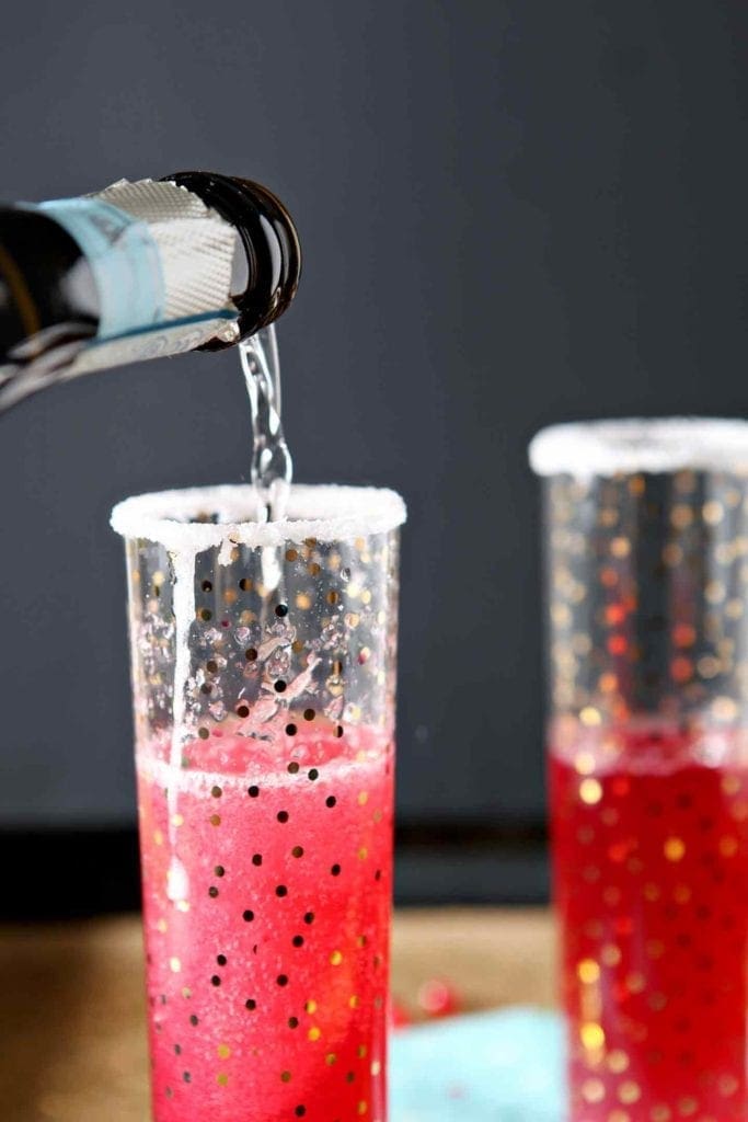 pouring champagne in a glass with pomegranate juice