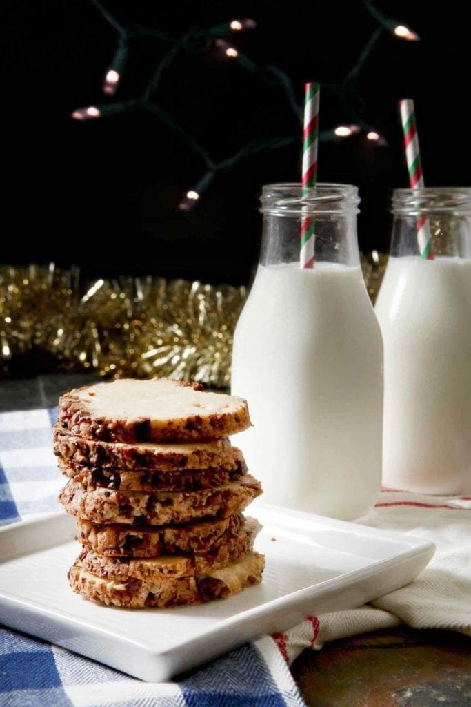 toasted pecan shortbread cookies stacked on a white plate with milk