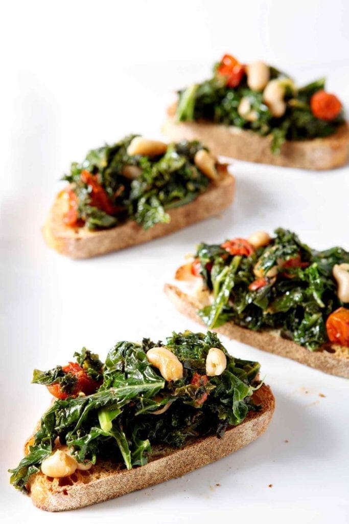 tuscan kale bruschetta on a white surface