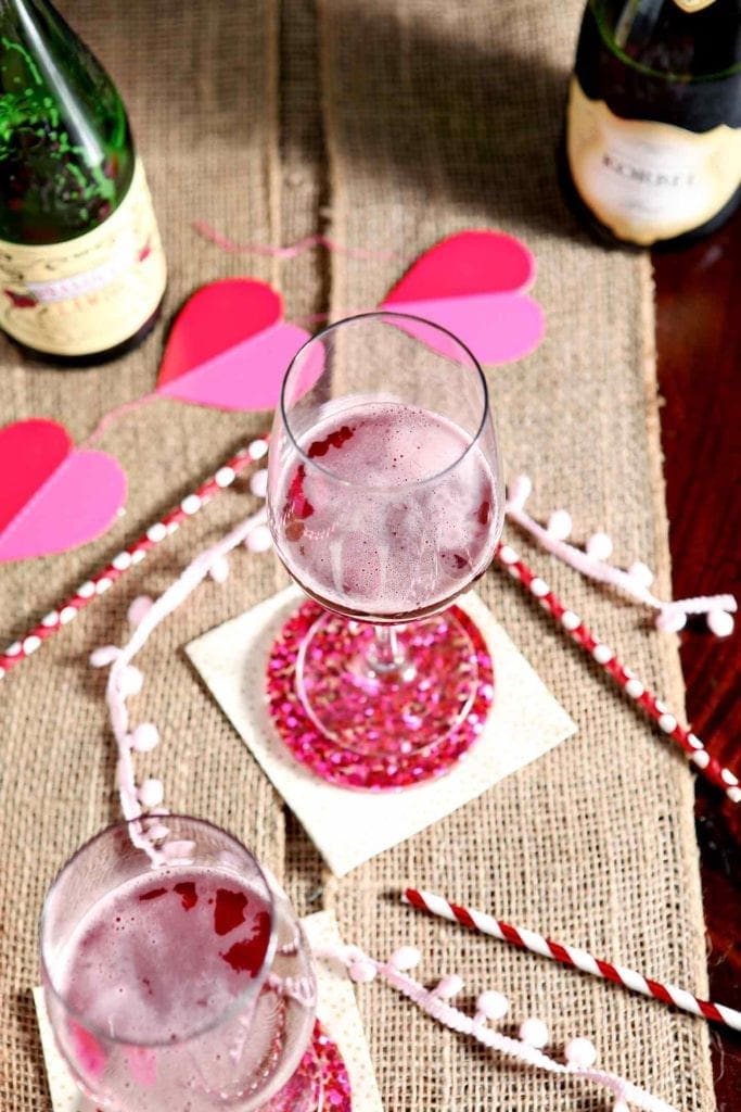 Overhead image of two Framboise Champagne Cocktails on a tabletop with Valentine's Day decorations around