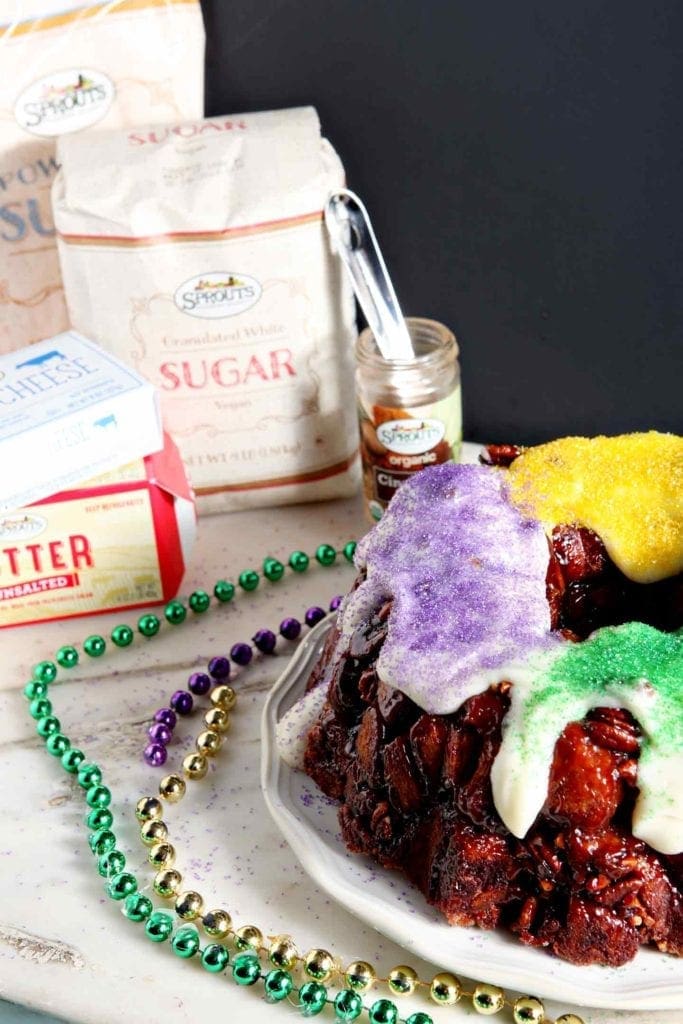 A praline king cake sits next to ingredients from Sprouts on a marble countertop