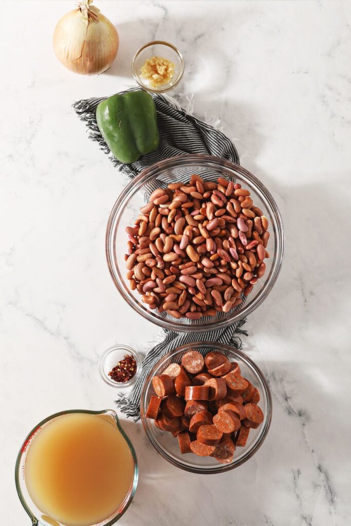 Beans, sausage and other ingredients in bowls on marble