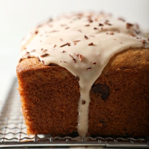 Icing drizzles down a loaf cake topped with chocolate shavings