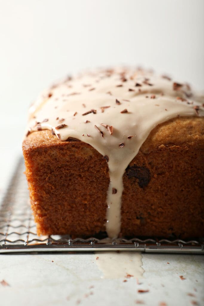 Icing drizzles down a loaf cake topped with chocolate shavings