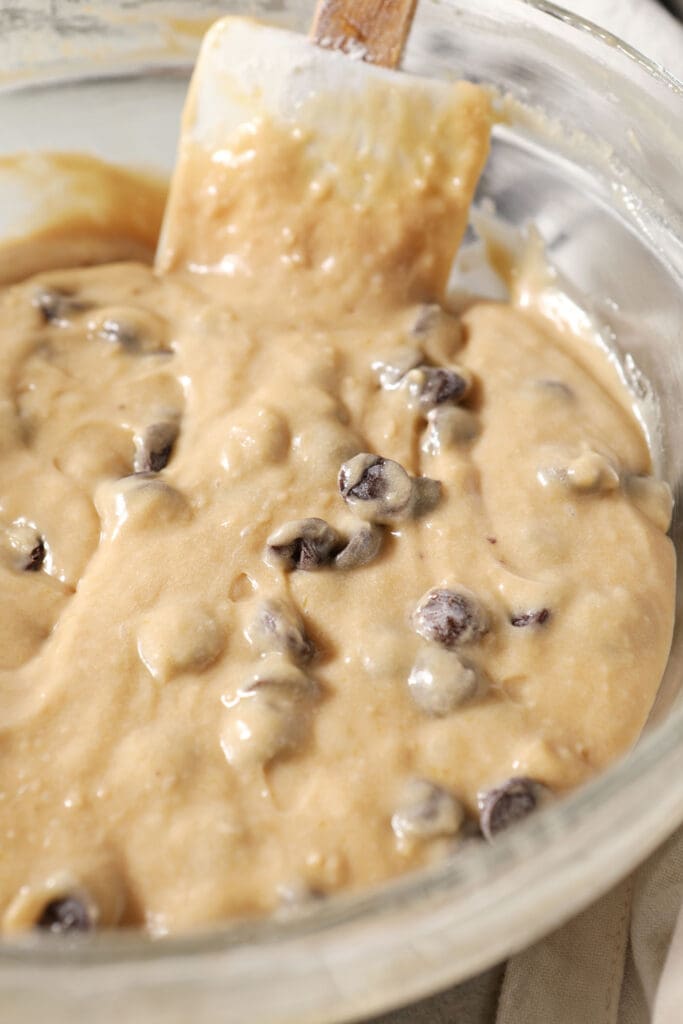 A rubber spatula mixes chocolate chips into cake batter