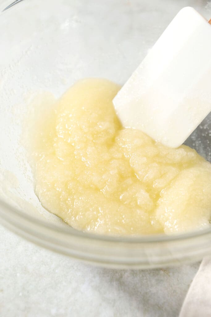 Sugar with wet ingredients in a bowl with a rubber spatula