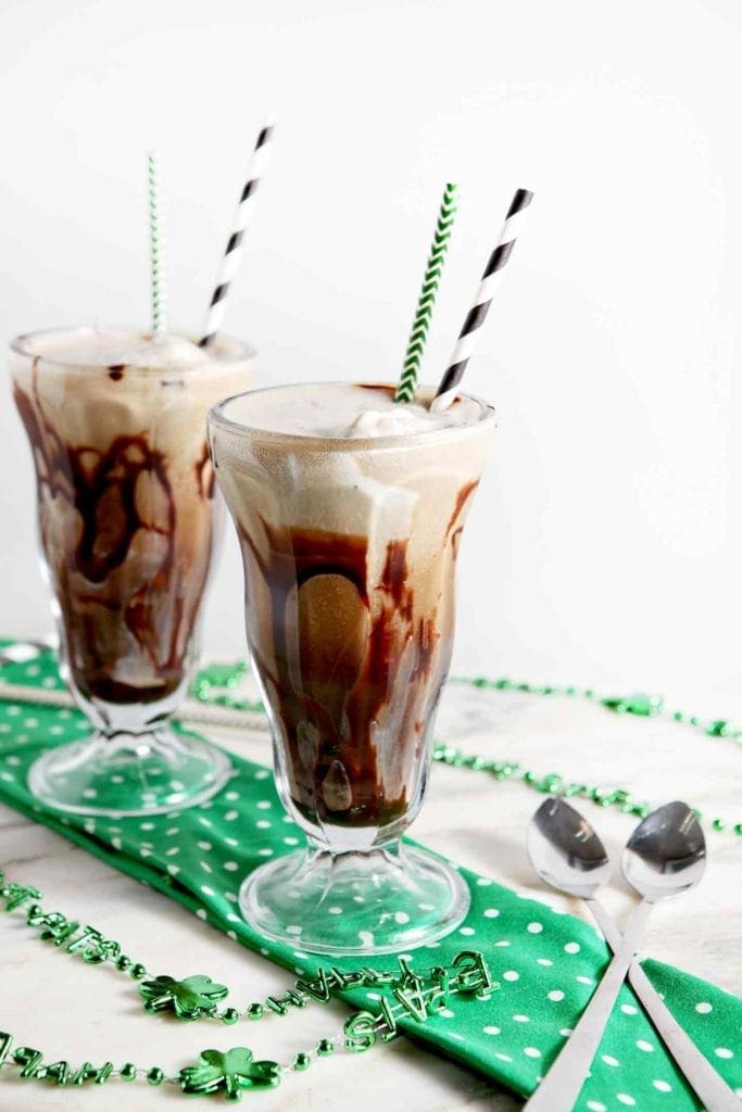 Two mint chip beer floats sit next to each other on top of a green napkin next to beads, spoons and straws