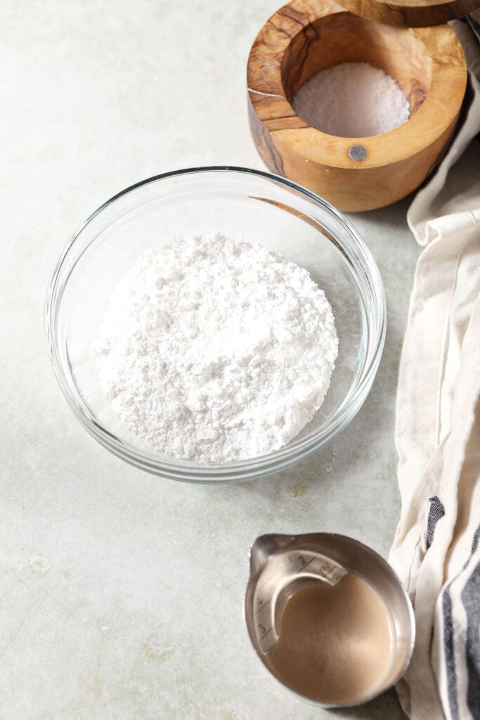 Ingredients to make frosting for a loaf cake in bowls on a green countertop