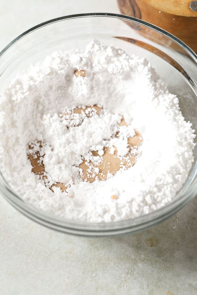 Irish cream poured into a bowl of powdered sugar on a green countertop