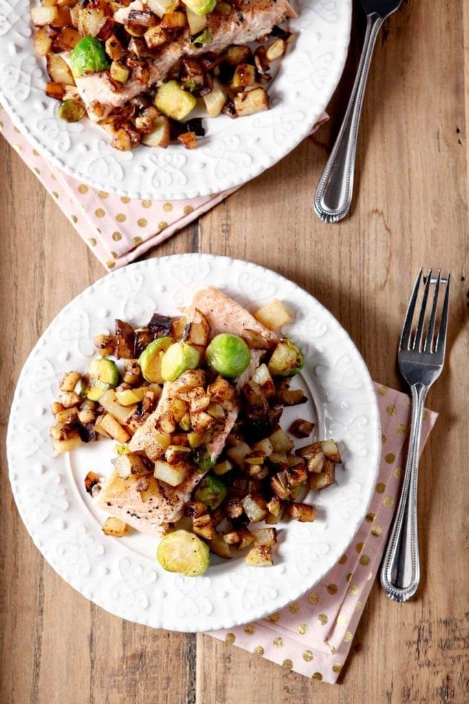 Winter vegetable hash over roasted salmon on white plates