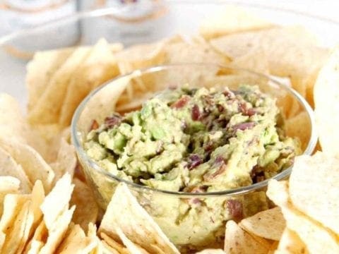 A bowl of guacamole surrounded by chips