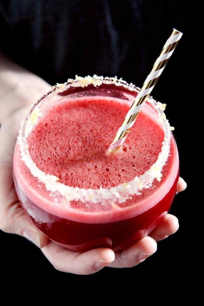 A woman holds a Cherry Lemonade Margarita in the palm of her hand