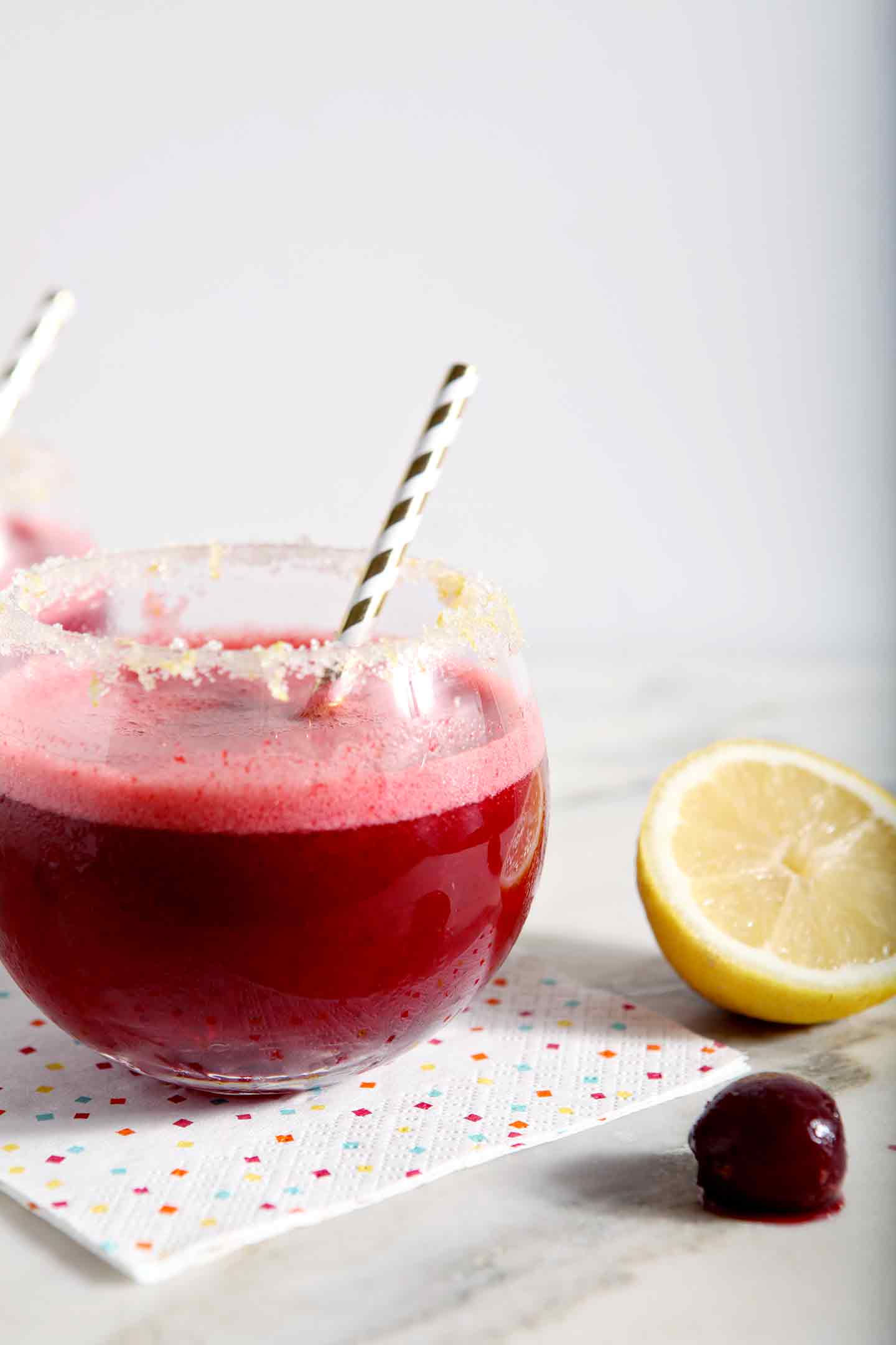 One lemonade margarita is shown, close up, with a lemon half and a cherry