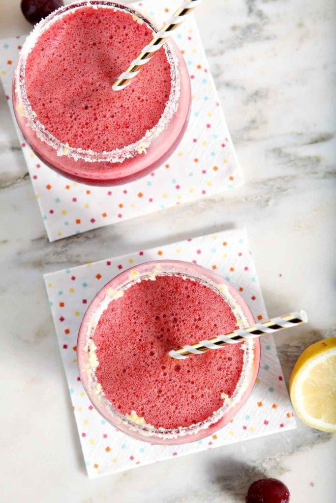 Overhead image of cherry margaritas, shown on napkins and with lemon slices