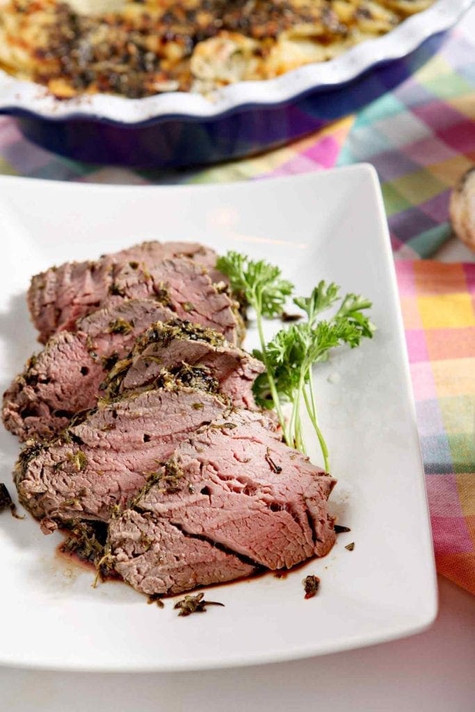 herb crusted beef tenderloin with parsley on a white plate