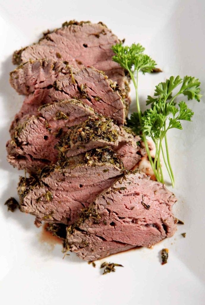 herb crusted beef tenderloin on a white plate