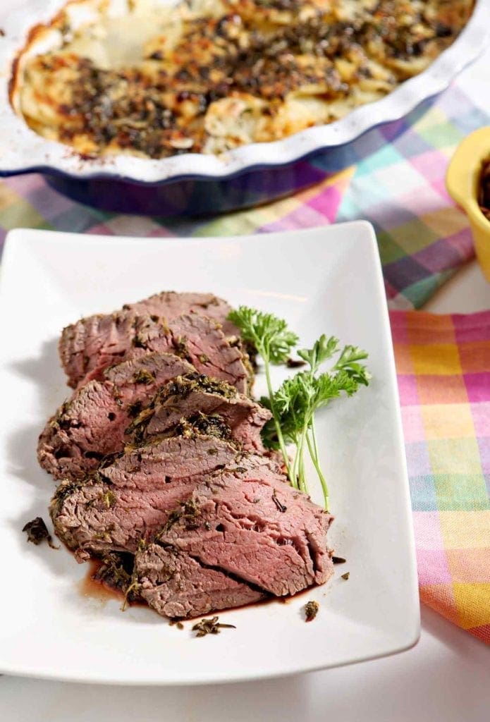 herb crusted beef tenderloin on a white plate