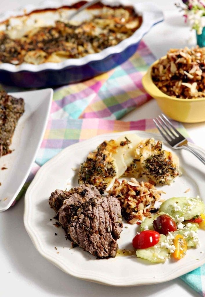 herb crusted beef tenderloin on a plate with side dishes