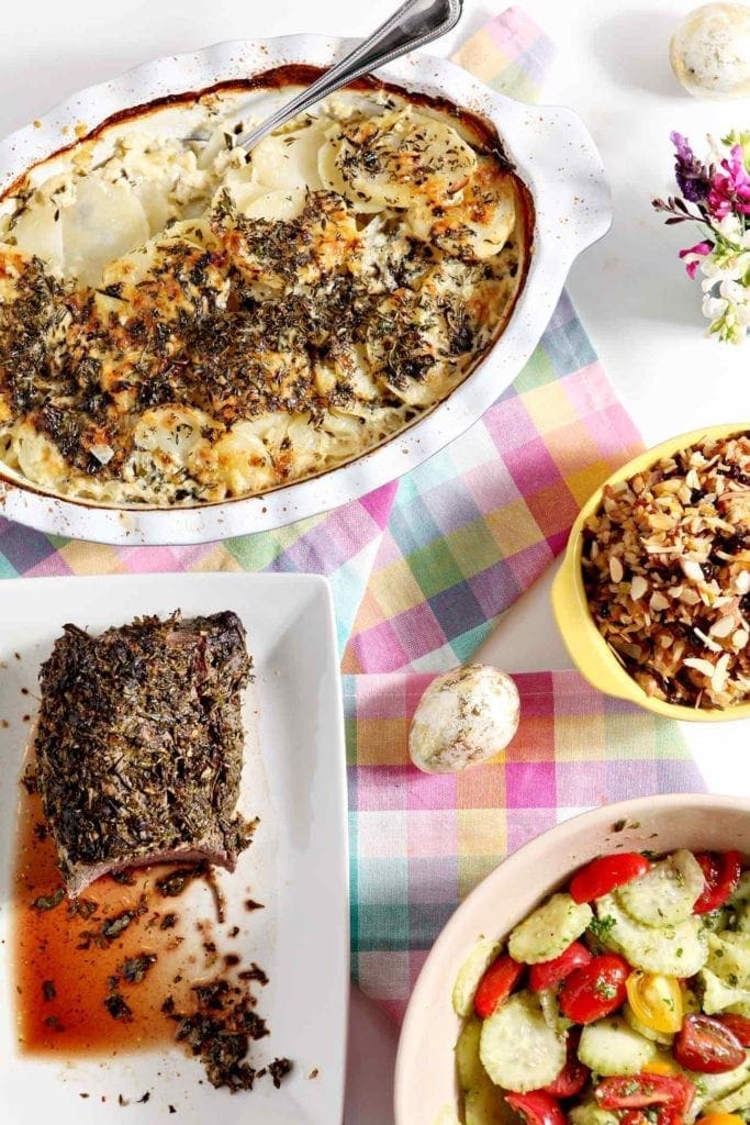 scalloped potatoes and herb crusted beef tenderloin on a table