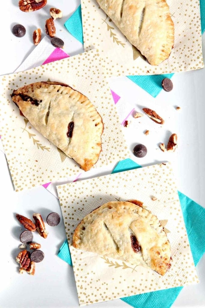 Three Chocolate Bourbon Pecan Hand Pies sit on a white platter before serving