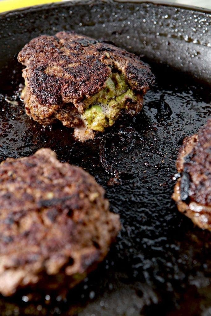 Close up of stuffed TexMex burgers cooking in a skillet