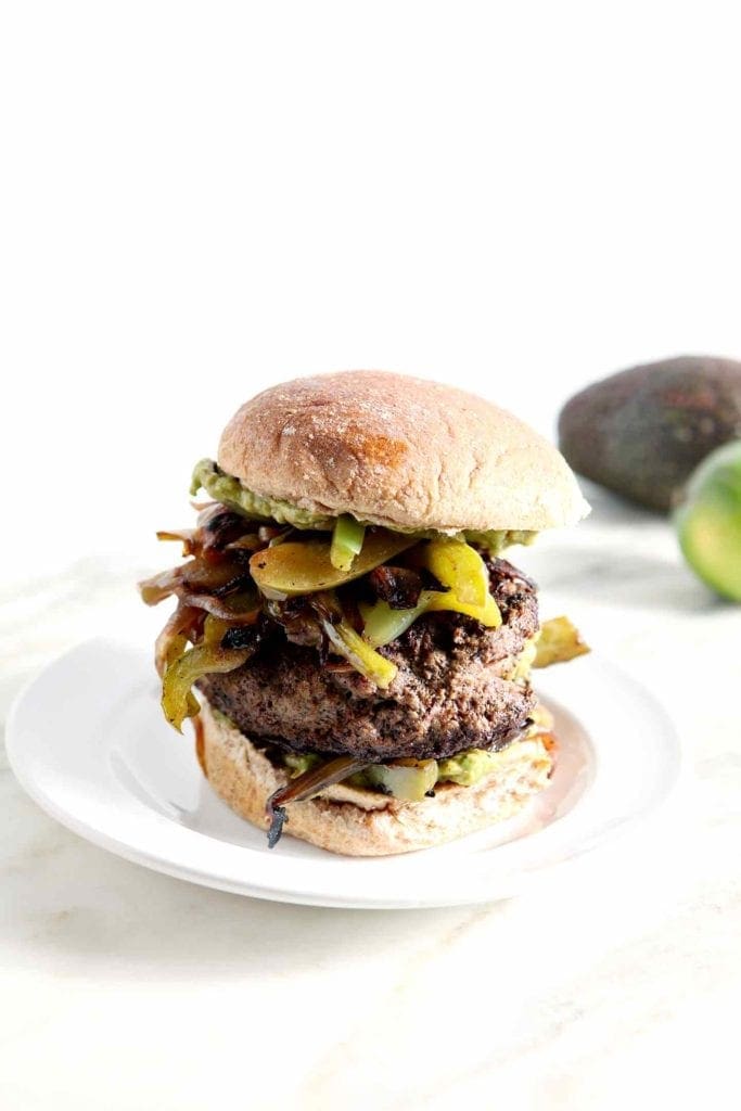 A Guacamole-Stuffed Fajita Burger is served on a white plate