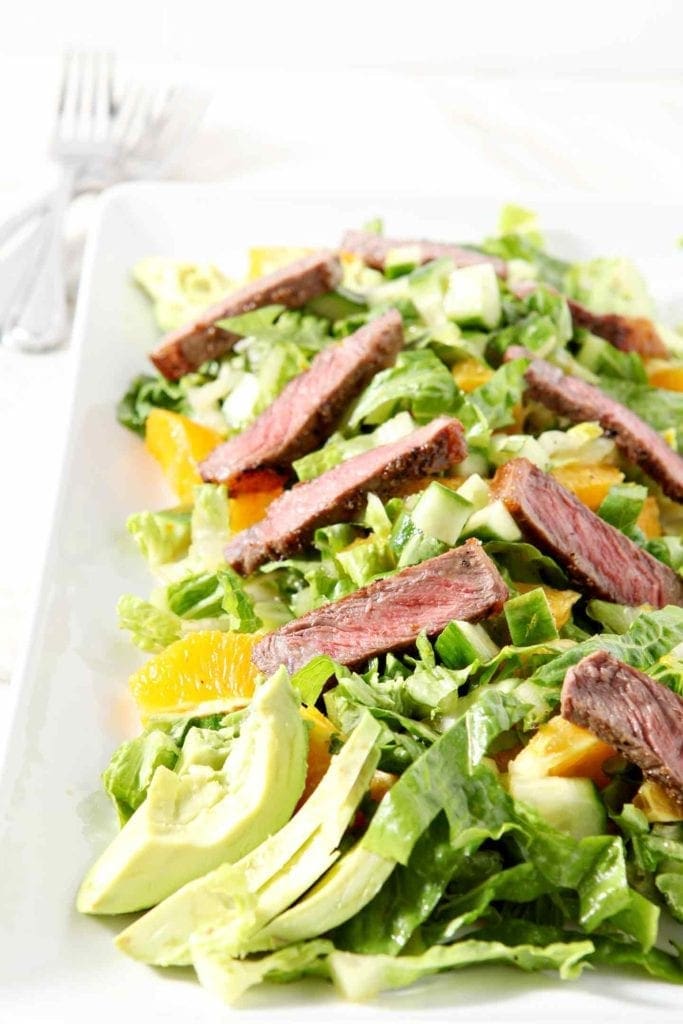 orange steak salad on a white plate