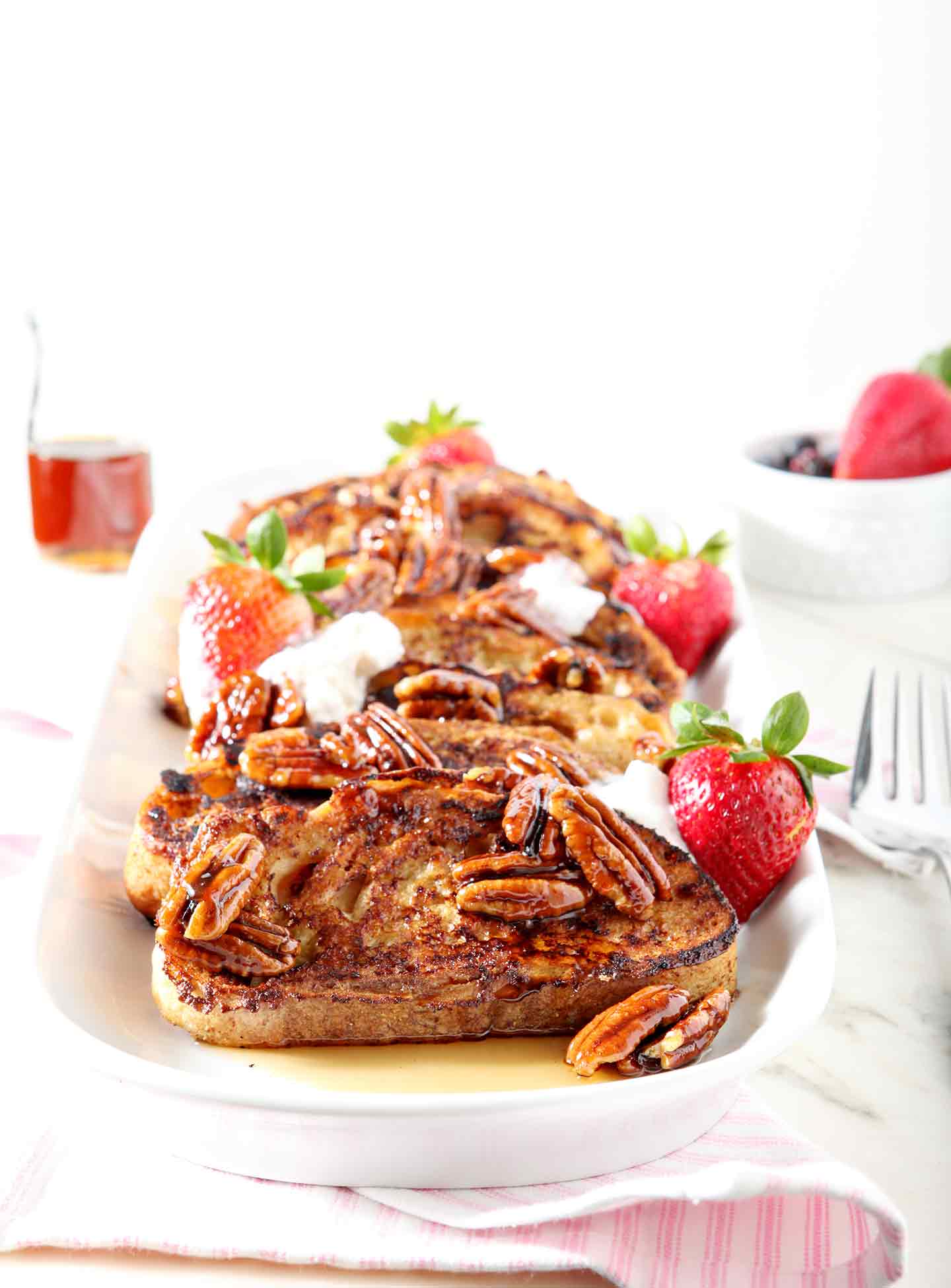 Praline French Toast is served on a platter with coconut cream and fresh strawberries