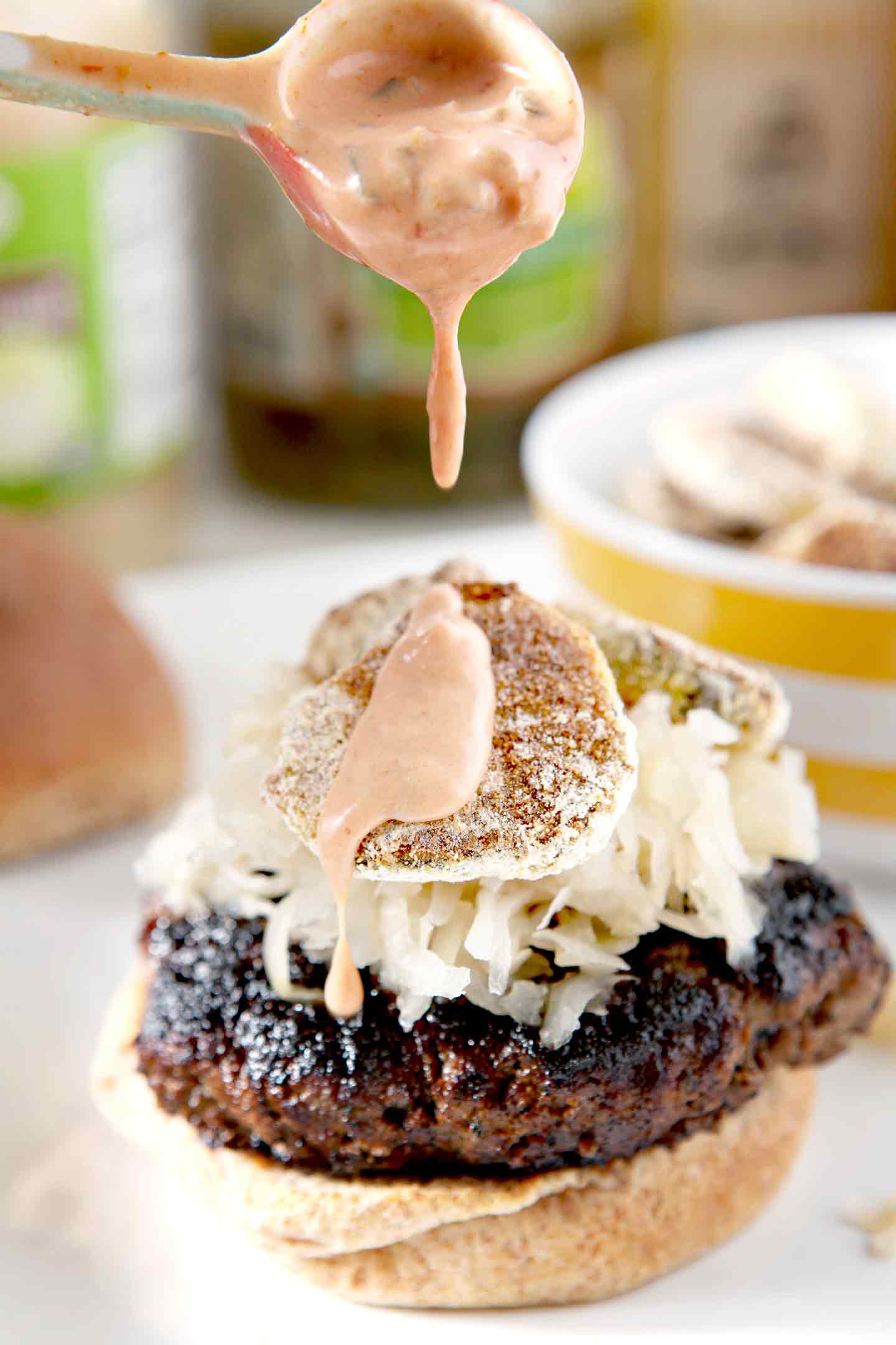 Close up of Sweet Sriracha Sauce being drizzled on top of a burger