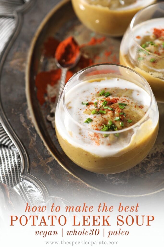 Close up of a clear glass bowl holding a serving of vegan potato leek soup garnished with additional coconut cream, paprika and chives with the text 'how to make the best potato leek soup. vegan | whole30 | paleo'