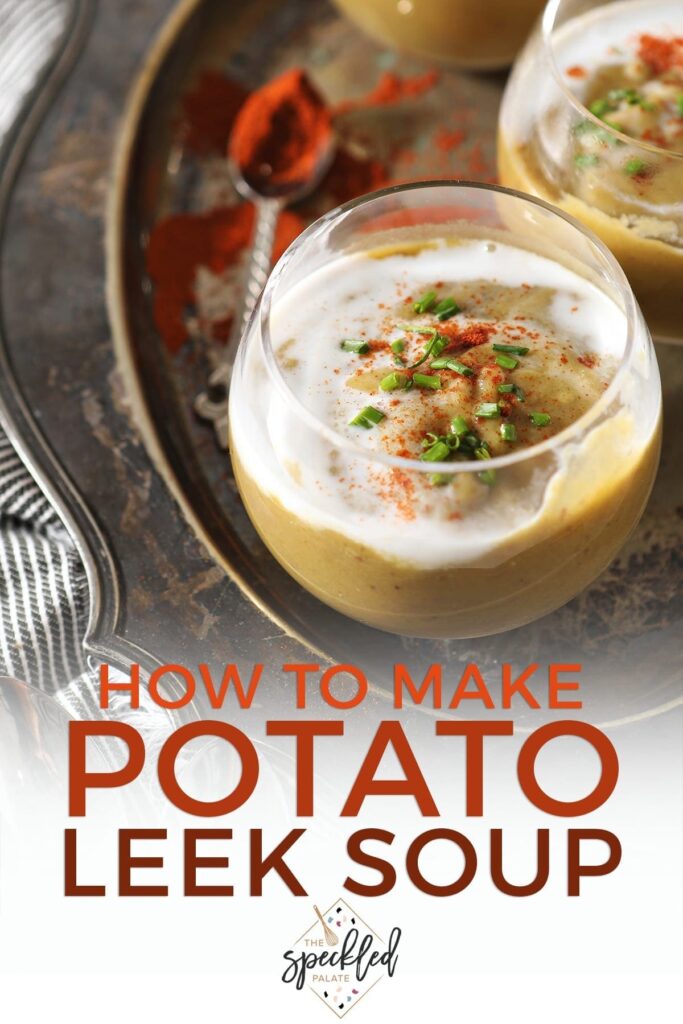 Close up of a clear glass bowl holding a serving of vegan potato leek soup garnished with additional coconut cream, paprika and chives with the text 'how to make potato leek soup'