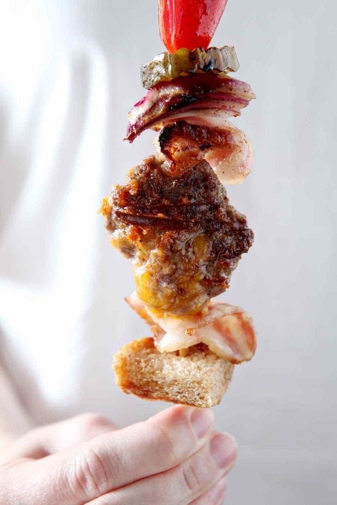 A woman holds a cooked Cheeseburger Kebabs in her hand