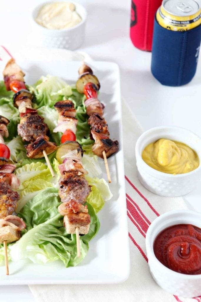 Cheeseburger kebabs are served on a white platter on top of lettuce