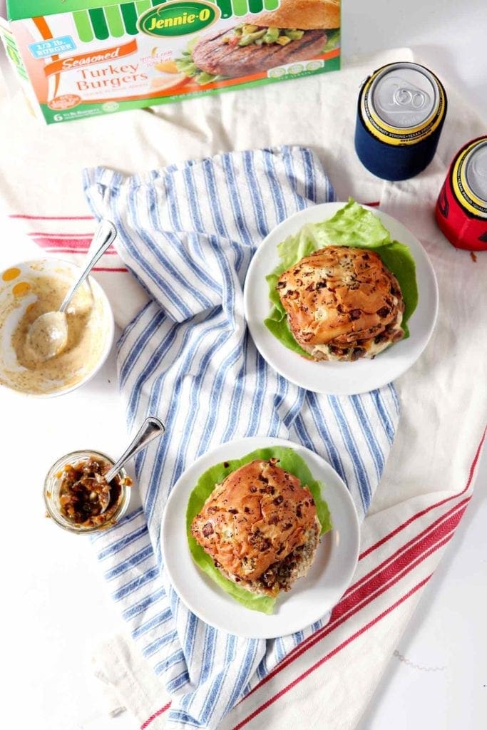 Two Louisiana Cajun Turkey Burgers with Ã‰touffÃ©e Relish and Creamy Cajun Sauce are served on a white background with all the fixings