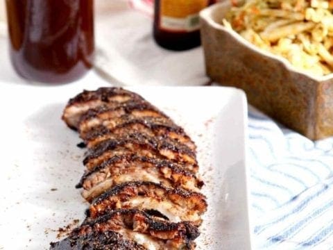 A platter of Memphis-Style Barbecue Ribs sits with barbecue sides on red, white and blue linen.