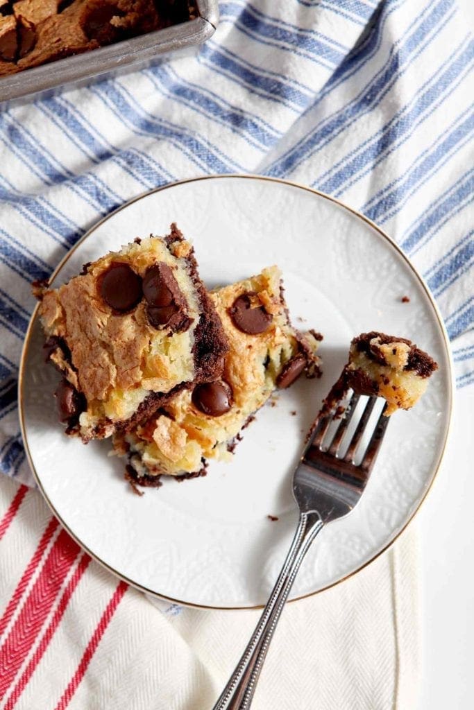 ooey gooey bars on a white plate with a fork