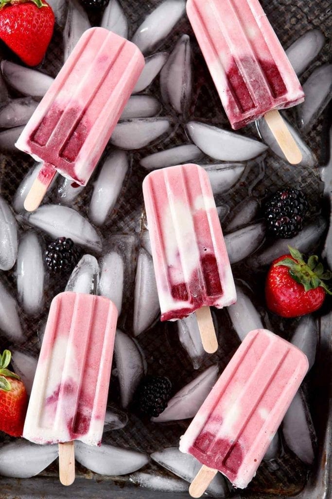 tri-colored paleo popsicles on ice cubes in a tray