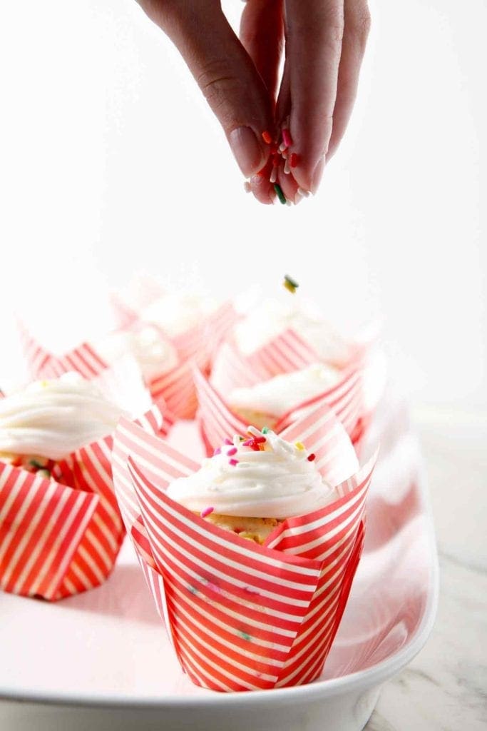 putting sprinkles on a funfetti cupcake