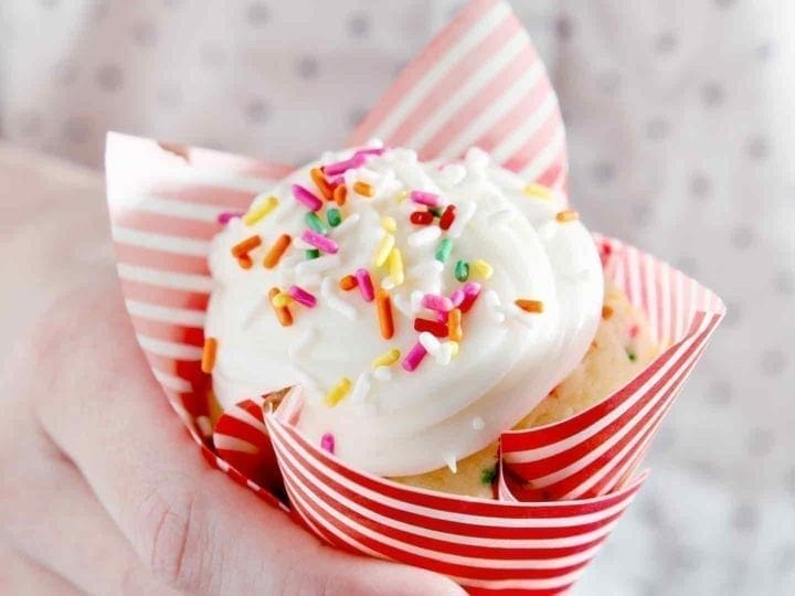 Hand holding a cupcake with sprinkles