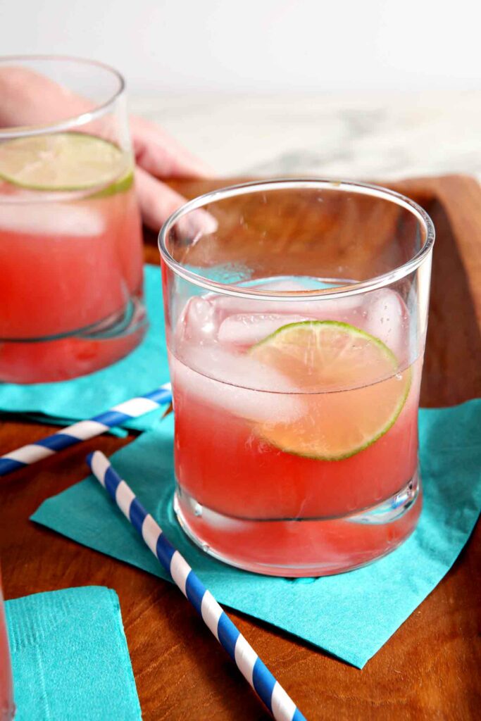 Close up of two glasses of Spiked Watermelon Limeade on a wooden tray