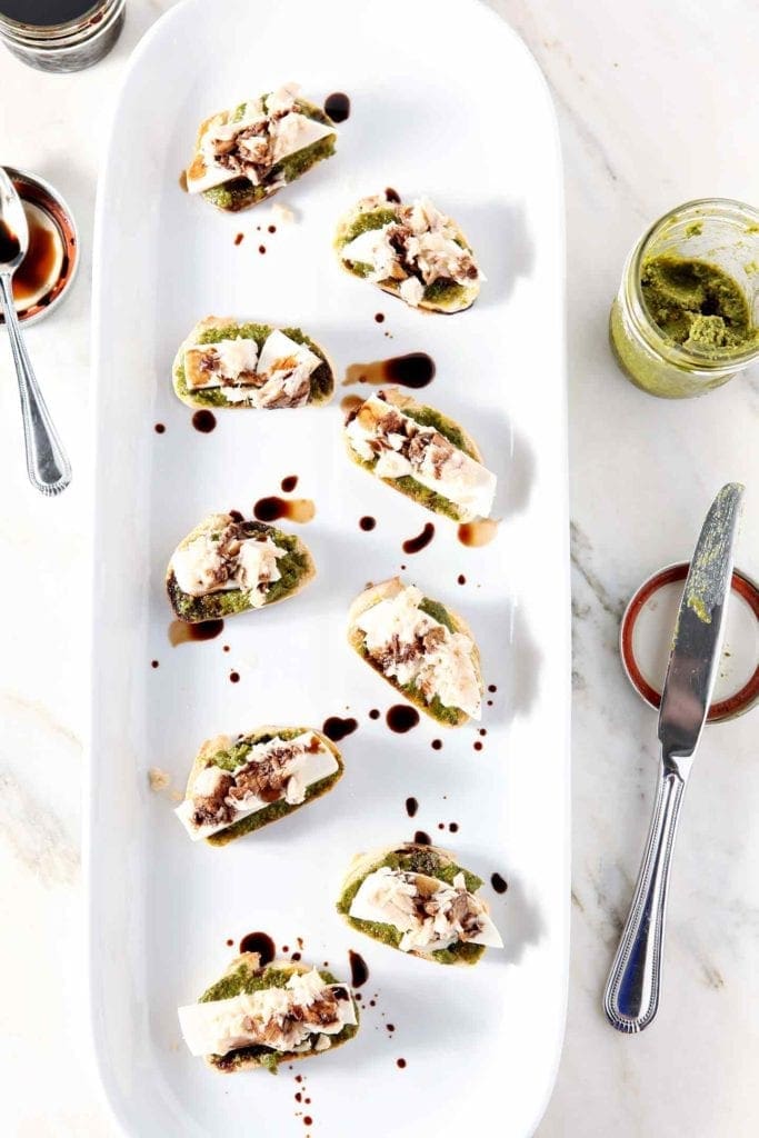 overhead photo of tuna pesto crostini on a white serving tray