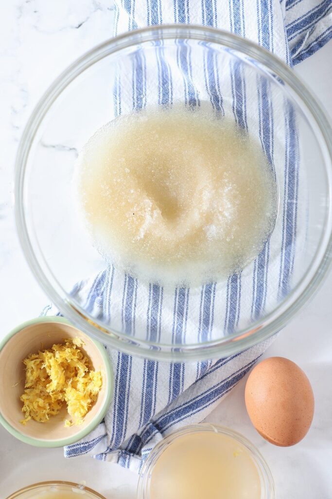 Wet ingredients with lemon zest, egg and more on a blue striped towel
