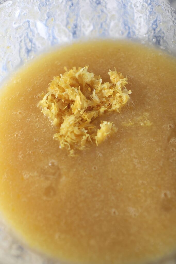Lemon zest on top of other wet ingredients in a clear glass bowl
