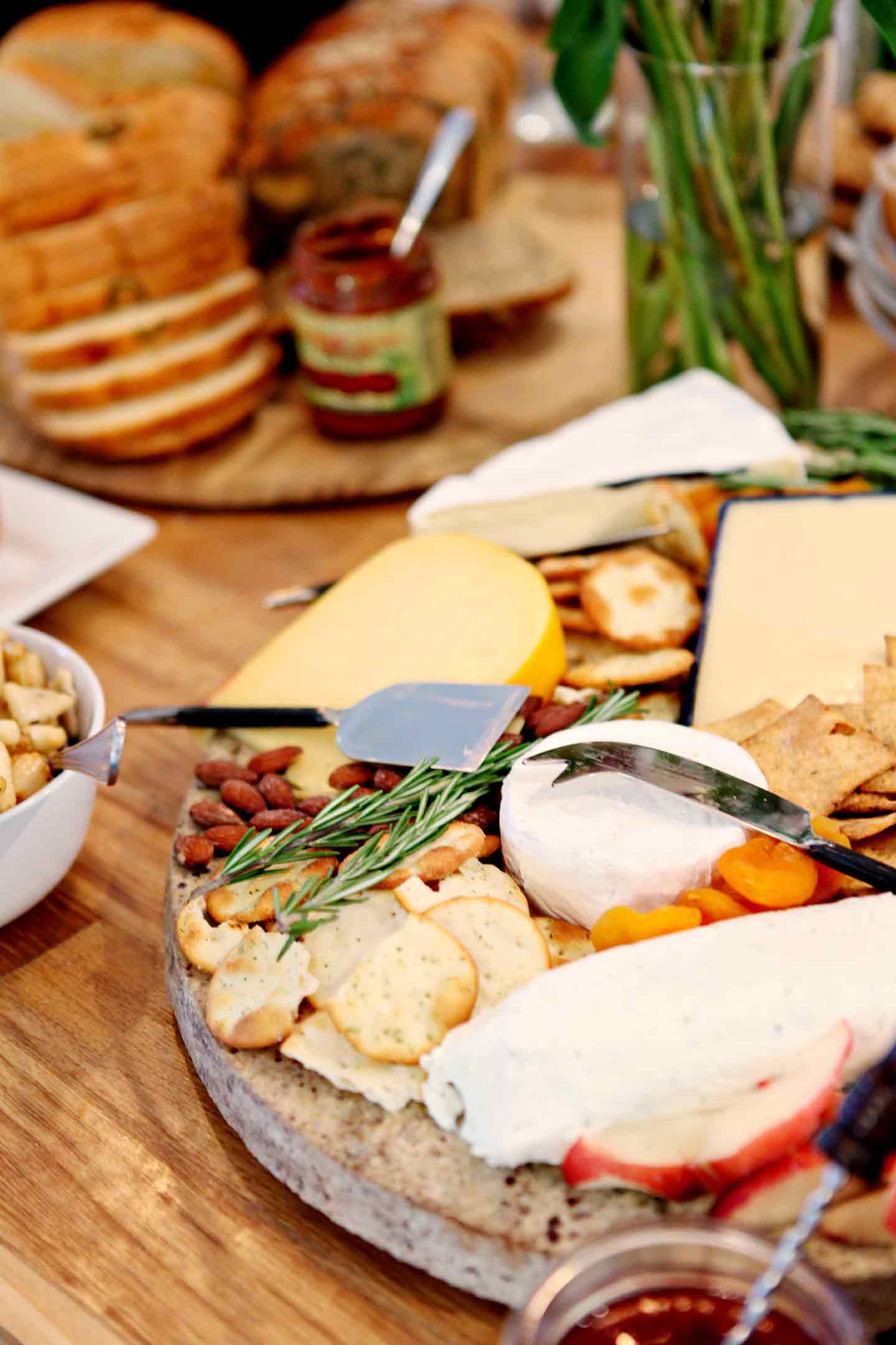 A cheese tray on a table with food at a potluck party