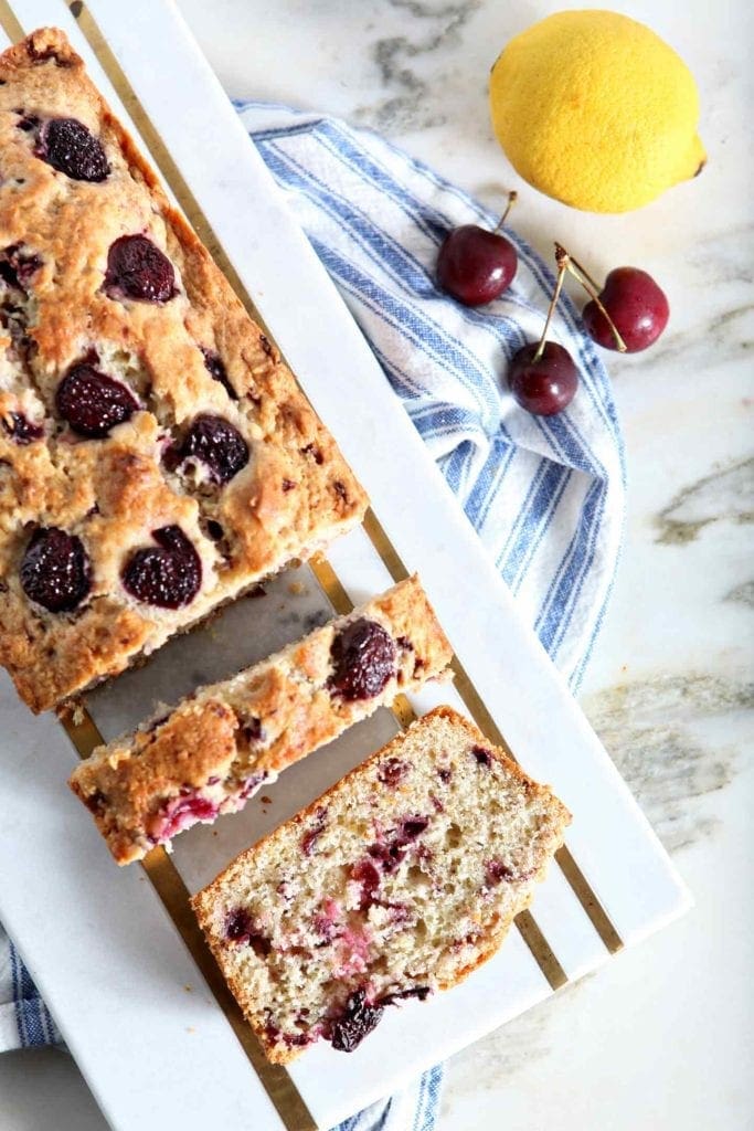 Slices of cherry bread on a marble tray over a blue and white striped towel