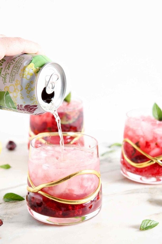 Ginger ale is poured into a Honeysuckle Cherry Smash Cocktail.