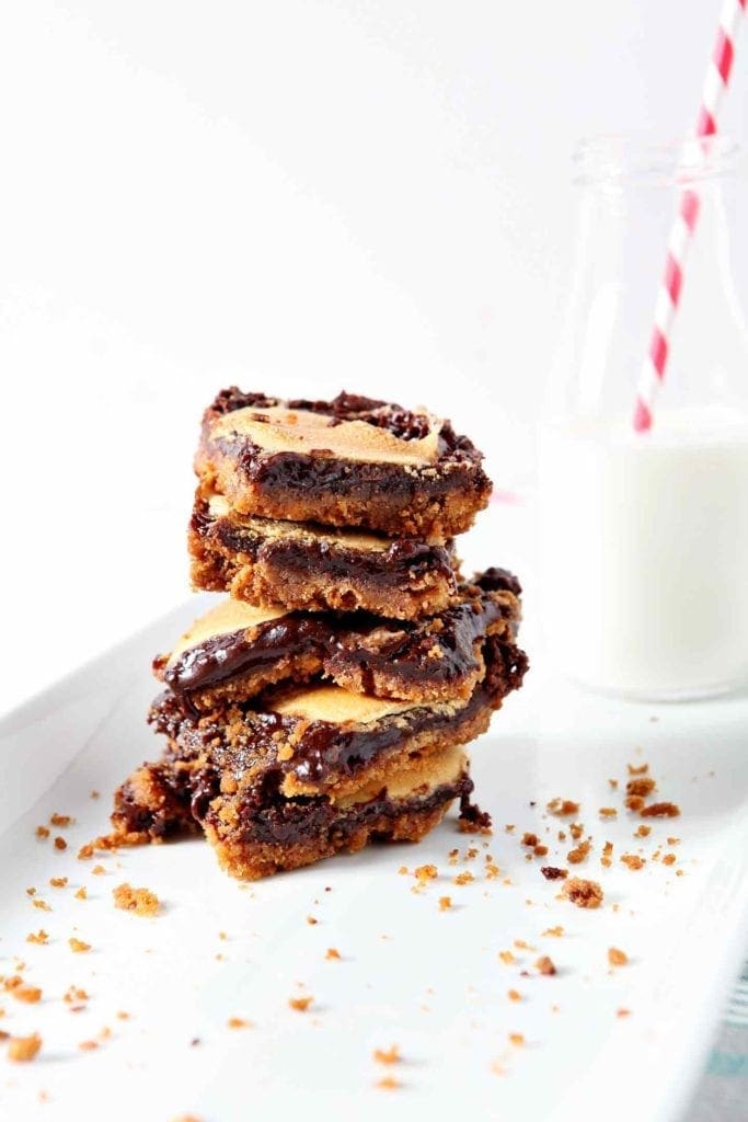 Several Mint Smores Bars are stacked on top of each other with a bottle of milk in the background