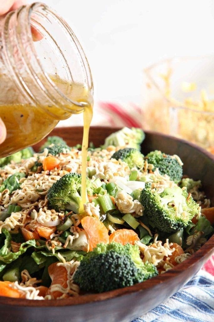 pouring dressing on ramen noodle clementine salad