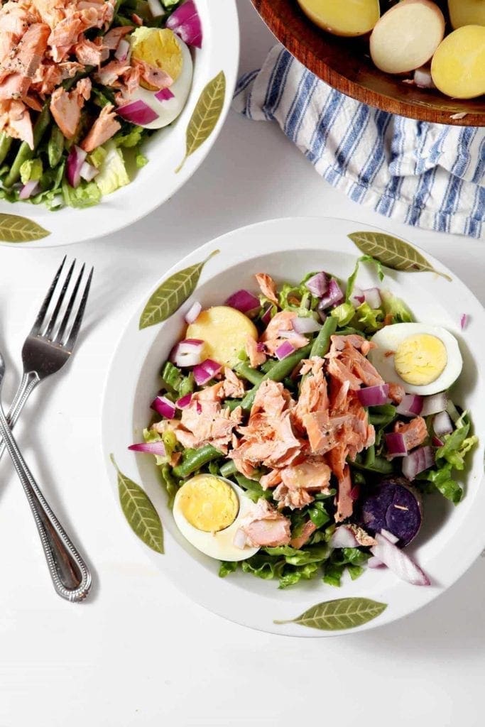 nicoise salad in a white bowl with forks